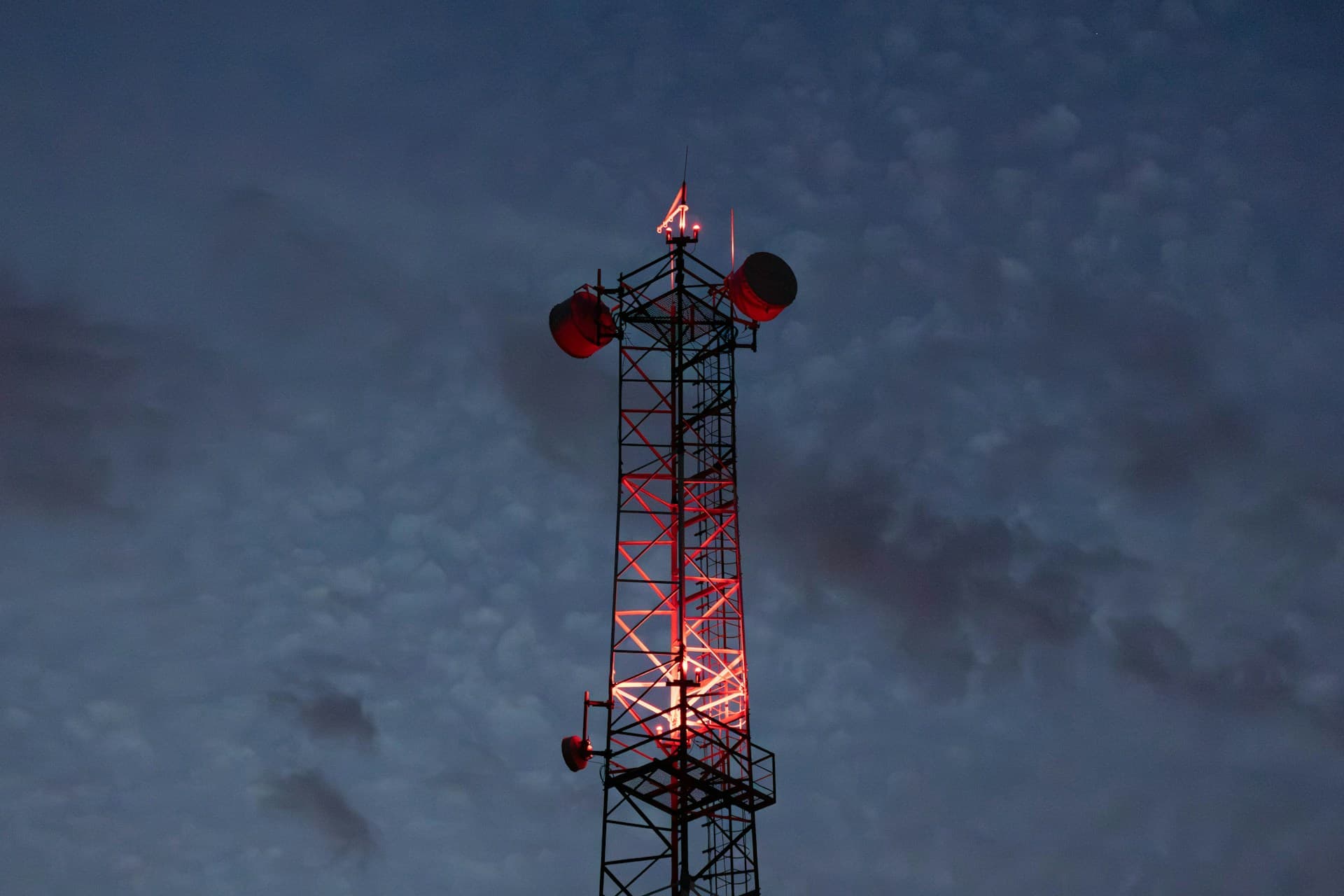 Red-lit communications tower against a dark sky