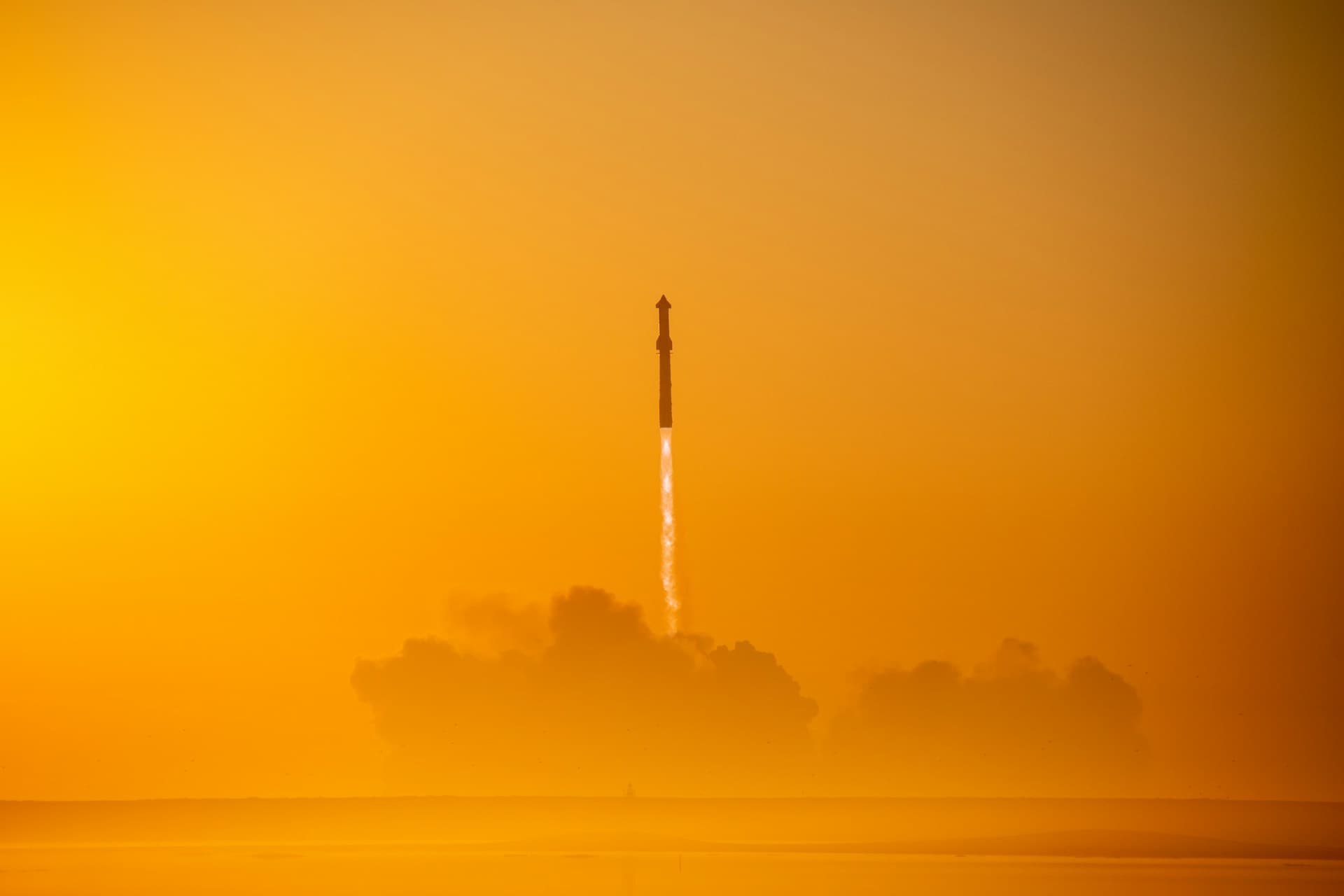 Rocket launching into an orange hazy sky at dusk